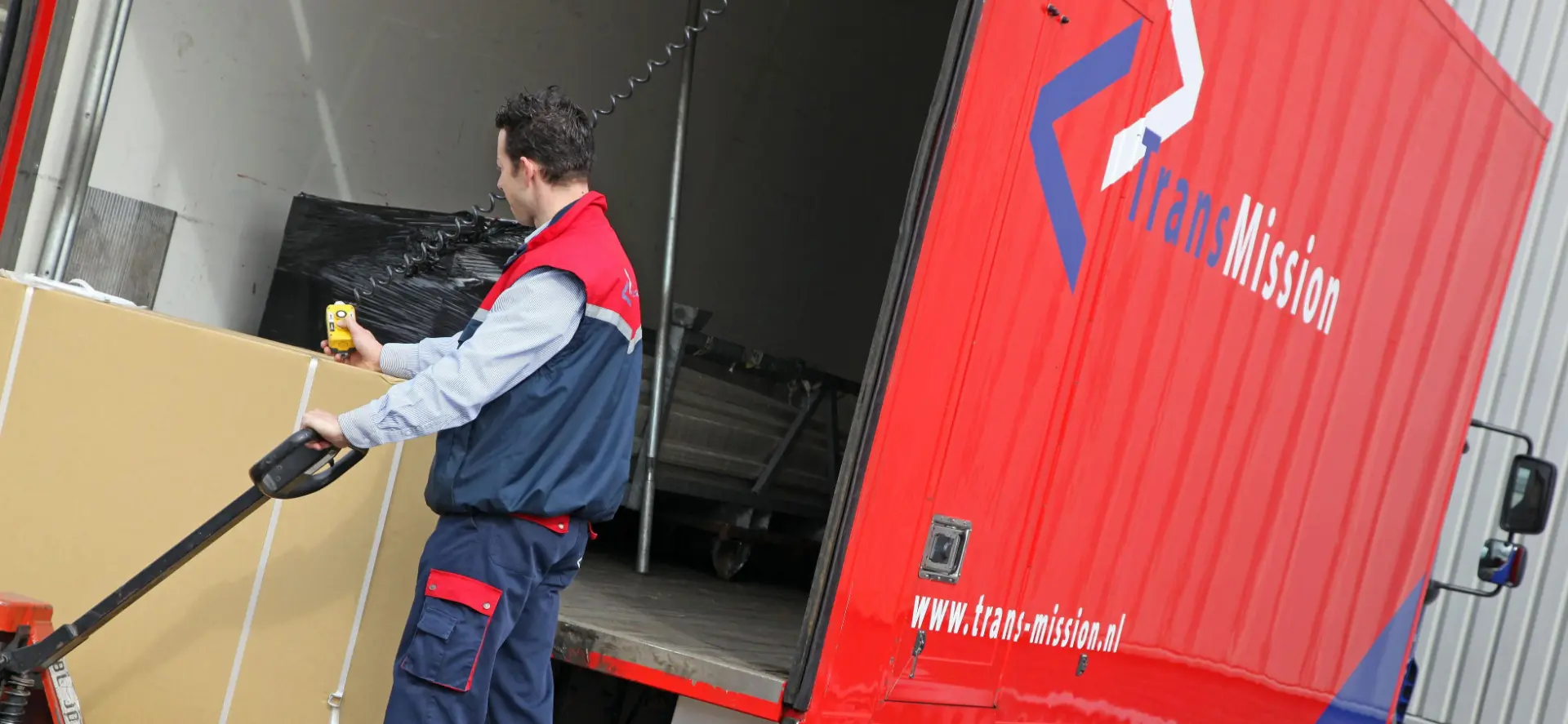 TransMission-medewerker laadt zendingen bij een rode distributievrachtwagen